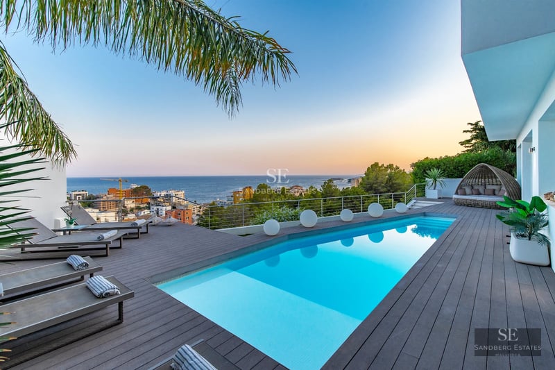 Panoramic view of a modern terrace with an infinity pool and elegant furniture. Stunning sea and horizon views.