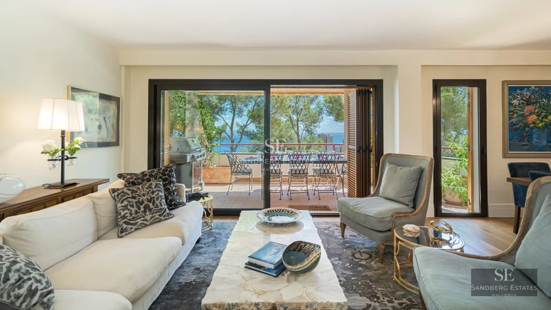 Exterior view of a modern house with a pool, garden and large windows reflecting sunlight.