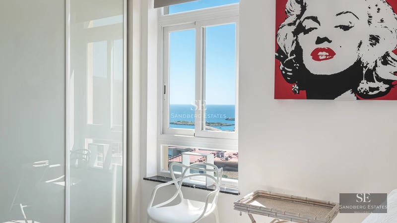 Panoramic view of a luxurious infinity pool surrounded by lush greenery and a modern house with large windows.