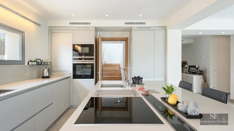 Spacious living room featuring panoramic windows offering a sea view. Modern sofa, textured rug, and ambient lighting.