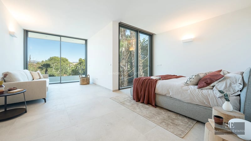 View of a modern villa featuring a pool, sun loungers, and lush gardens. Contemporary architecture with large windows.