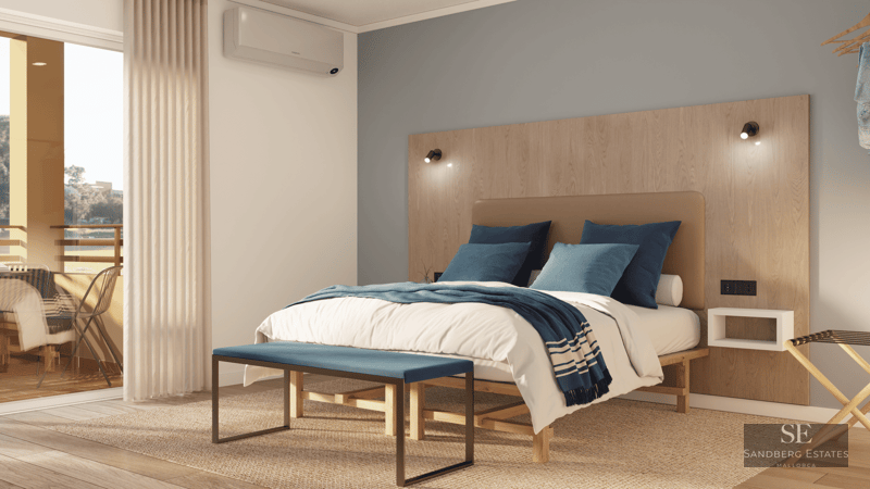 Chambre lumineuse avec grand lit, tête de lit en bois, banc bleu et accès à une terrasse ensoleillée.