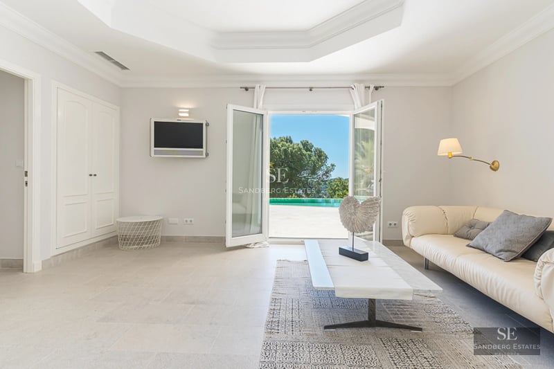 Bright living room with panoramic windows, grey sofas, wooden coffee table, and parquet flooring. Exterior view.
