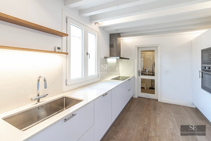 Spacious living room with floor-to-ceiling windows, modern sofas and access to a terrace with a view. Light wooden floors, abundant natural light.