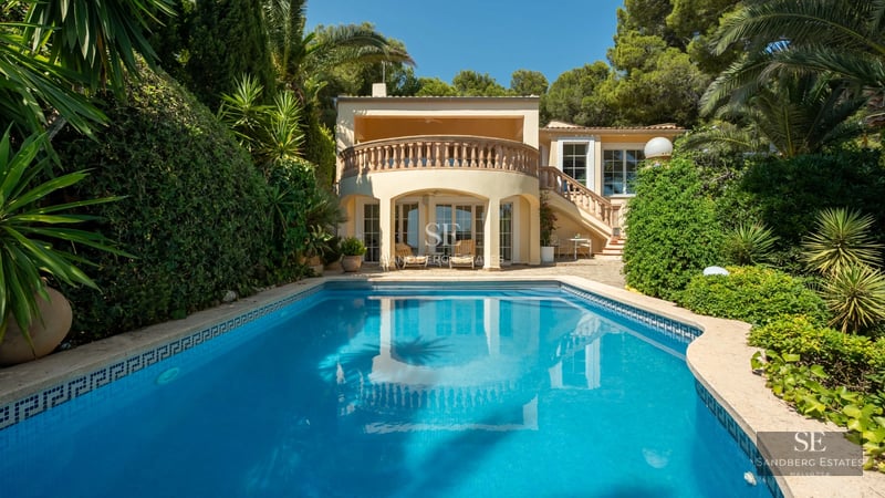 Spacious living room with floor-to-ceiling windows, designer sofas, wooden coffee table, textured rug and panoramic sea view.