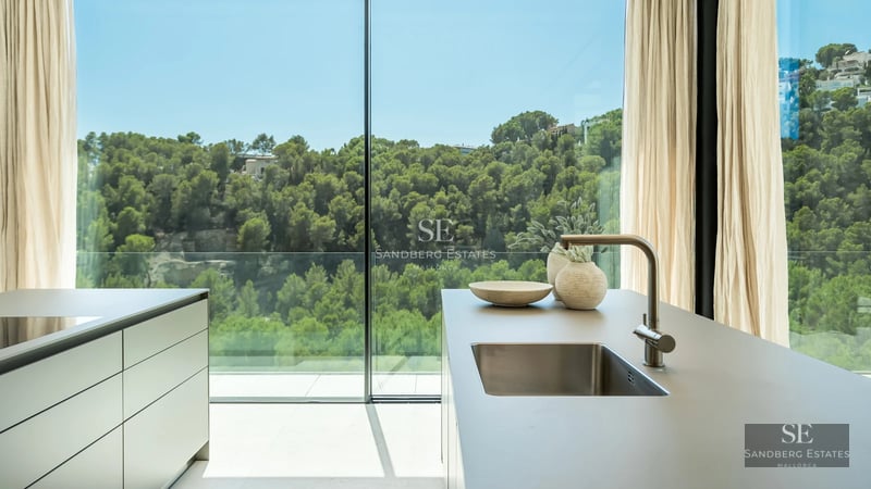 Exterior view of a modern villa with an infinity pool, large windows, and minimalist design. Lush garden and blue sky.