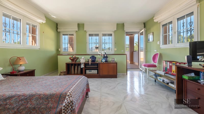 Exterior view of a modern villa with infinity pool, lush garden, and minimalist architectural design. Large windows and sunny terrace.