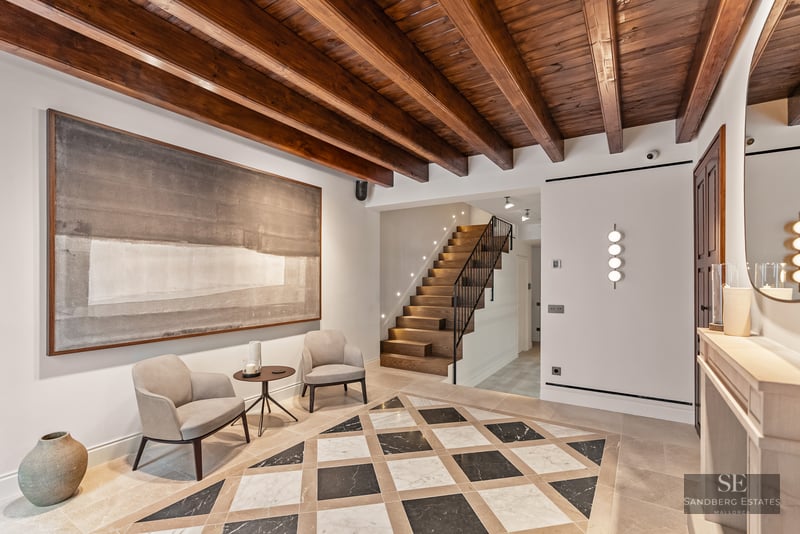 Luxury entrance hall featuring patterned marble floors, wooden beamed ceiling, and a modern wooden staircase.