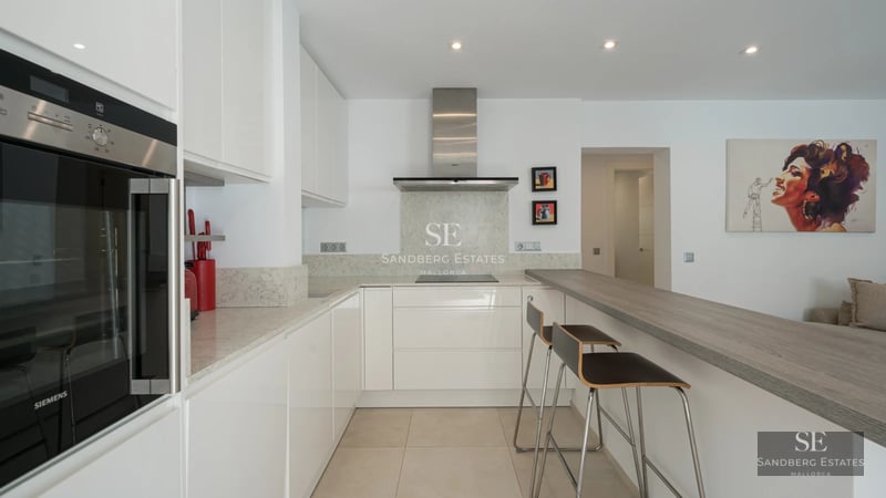 Spacious living room with panoramic windows, light wood floors, modern designer furniture, and abundant natural light.