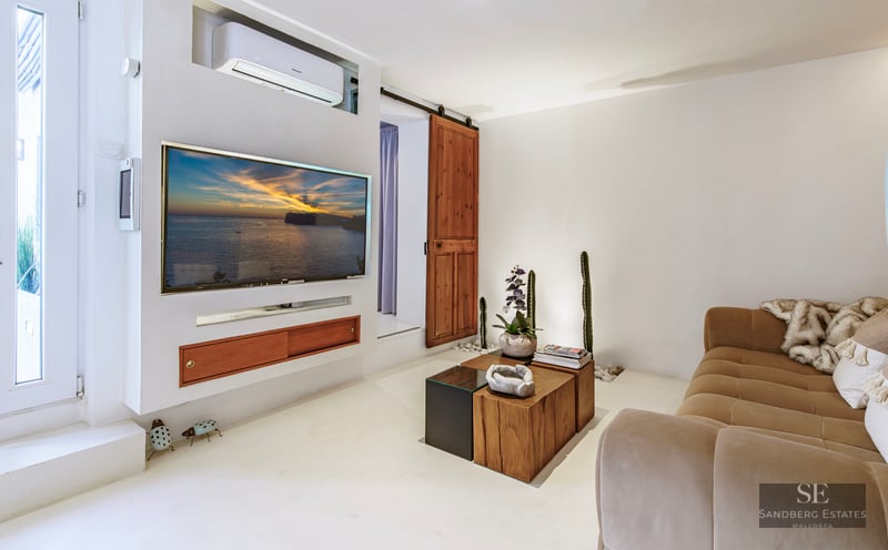 Cozy white living room featuring a wall-mounted TV, a large beige sofa, and a rustic wooden sliding barn door.