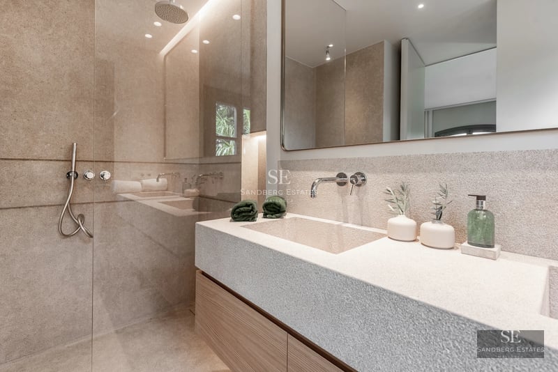 Spacious terrace featuring a pool, sun loungers, and views of a lush garden. Modern, minimalist architecture.