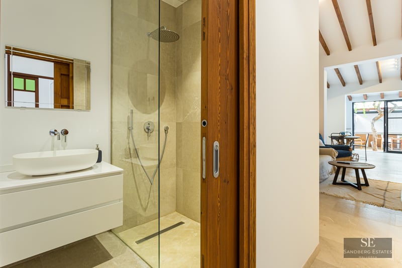 Contemporary bathroom featuring a stone walk-in shower, white vanity with vessel sink, and a sliding wooden door.