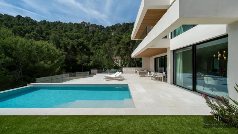 Exterior view of a modern villa with a pool, lush garden, and large windows. Minimalist and elegant design.