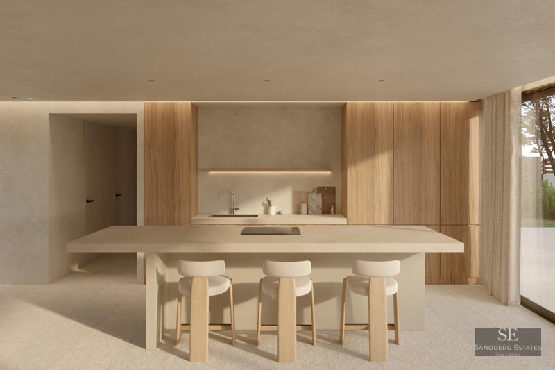 Modern minimalist kitchen featuring a large beige island, light wood cabinetry, and three stylish bar stools in a bright space.