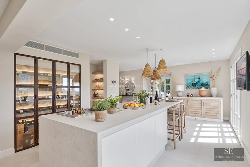 Spacious living room with large windows, light wood floors, and minimalist decor. Panoramic sea views from the balcony.