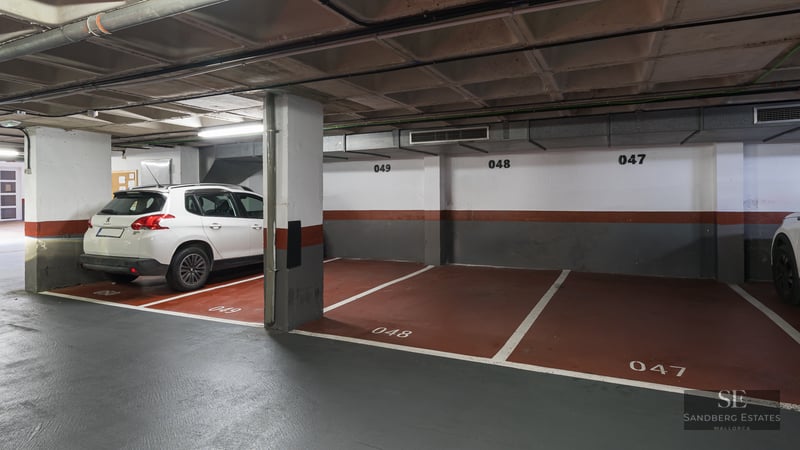Indoor parking garage with numbered spaces and a white SUV parked next to concrete pillars.