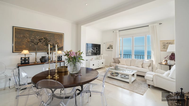 Spacious living room with sea views, balcony, and modern design. Light wood floors, gray sofas, and design details.