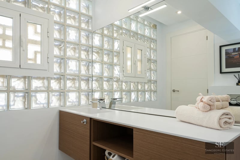 Spacious living room featuring floor-to-ceiling windows offering panoramic sea views, light wood floors, and modern neutral-toned furniture.