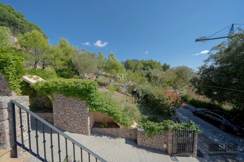 Spacious balcony with glass railing and wood flooring. Panoramic views of the sparkling blue sea. Modern outdoor furniture.