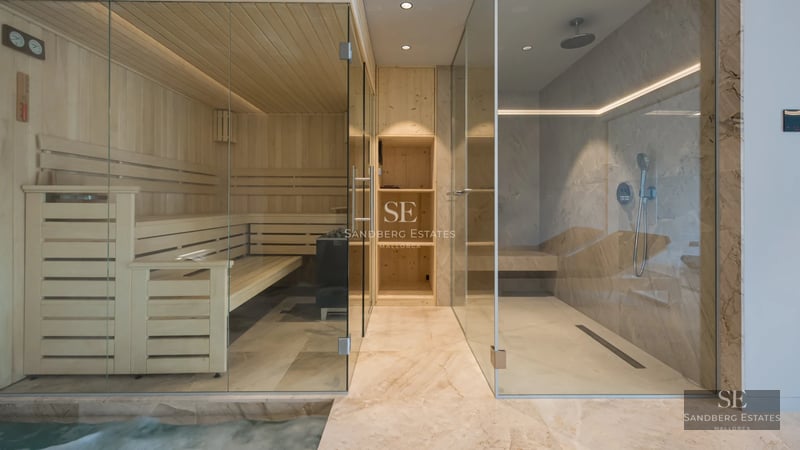 Spacious living room with large windows, light wood floor, modern sofa, and panoramic sea view. Minimalist and elegant design.