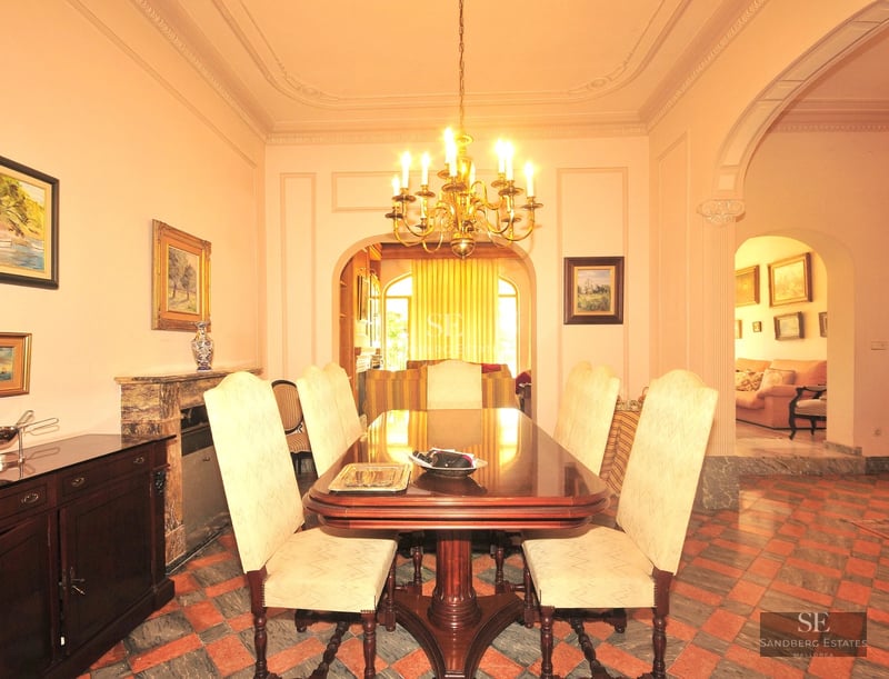 Exterior view of a modern villa featuring an infinity pool, wooden deck, large glass windows, and lush garden. Minimalist architecture.