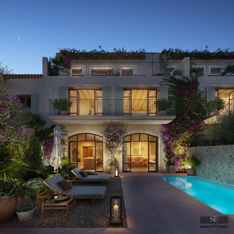 Luxury villa at twilight featuring a glowing blue pool, sun loungers, stone walls, and climbing bougainvillea plants.