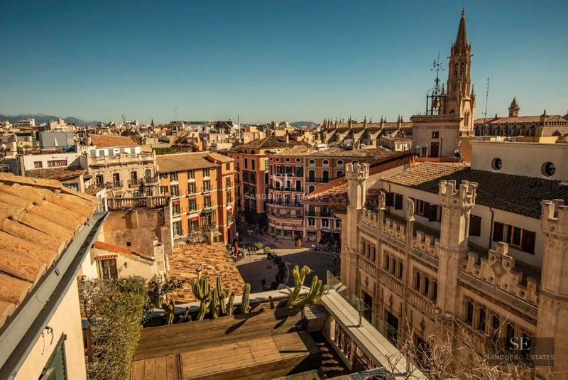 Spacious balcony with sea view, furnished with wicker and wood furniture. Awning for shade and modern glass railing.