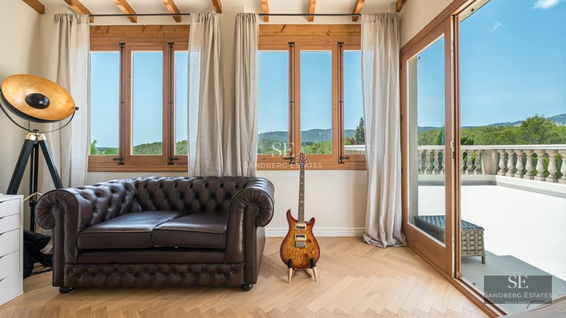 View of infinity pool with glass edge, sun loungers, and sea view from a modern terrace with lush vegetation.