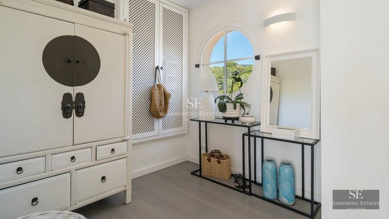 Spacious living room featuring floor-to-ceiling windows, modern fireplace, beige sofas, light rug and panoramic views. Minimalist and elegant design.