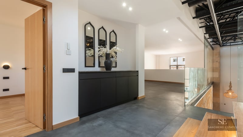 Modern hallway with black cabinetry, arched mirrors, grey tile floors, and a glass railing overlooking the lower floor.