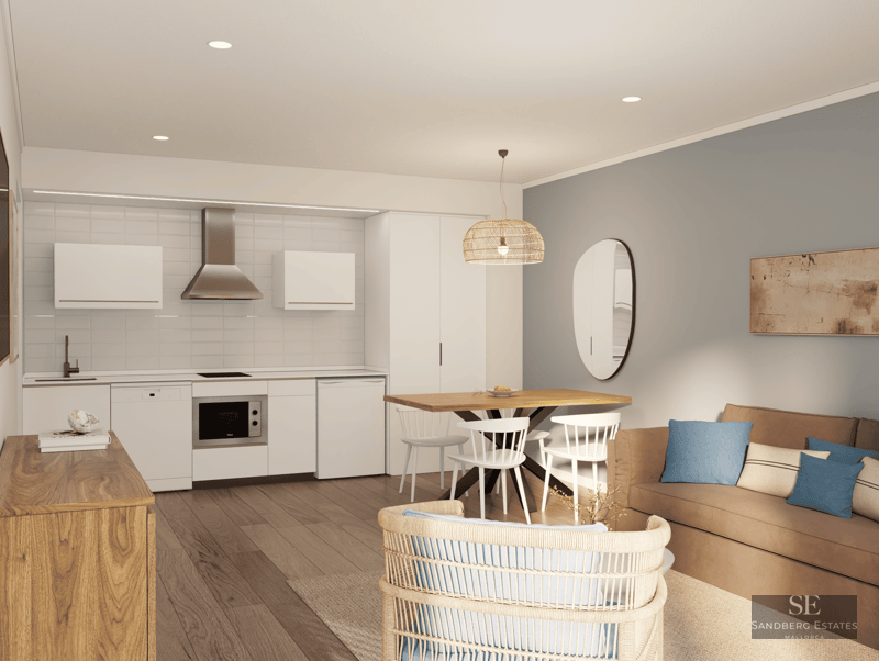 Modern open-plan living room featuring a white kitchen, wooden table, and tan sofa with blue cushions.