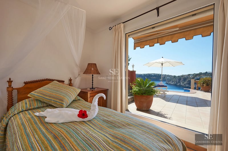 Panoramic view from an elegant balcony with modern furniture and ocean view. Glass railing, wooden floor.