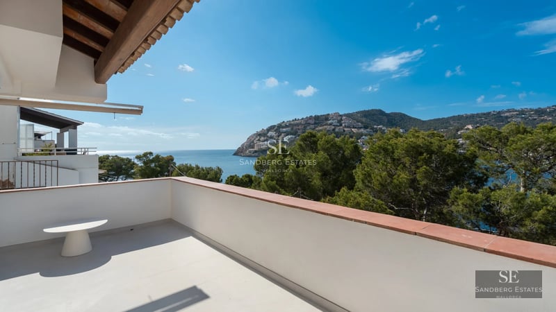 Spacious balcony with sea view, modern furniture, glass railing and wooden floor, part of a luxury apartment.