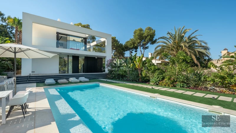 Large reflecting pool surrounded by manicured lawn. Modern facade with large windows and minimalist architecture.