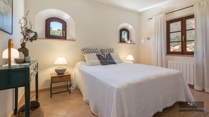 Spacious living room with large windows, natural light and modern furniture. Light wood floors, elegant rug, and fireplace. Garden view.