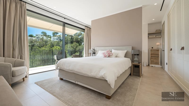 Spacious living room with floor-to-ceiling windows, modern fireplace, designer sofas, warm lighting, and access to a terrace with views.