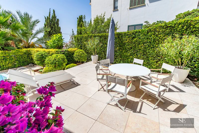 Exterior of a modern villa with a reflecting pool, surrounded by greenery. Minimalist design, large windows, and sleek terrace.