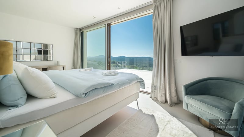 Exterior view of a modern villa with infinity pool, large windows, and minimalist architecture. Lush garden and clear sky.