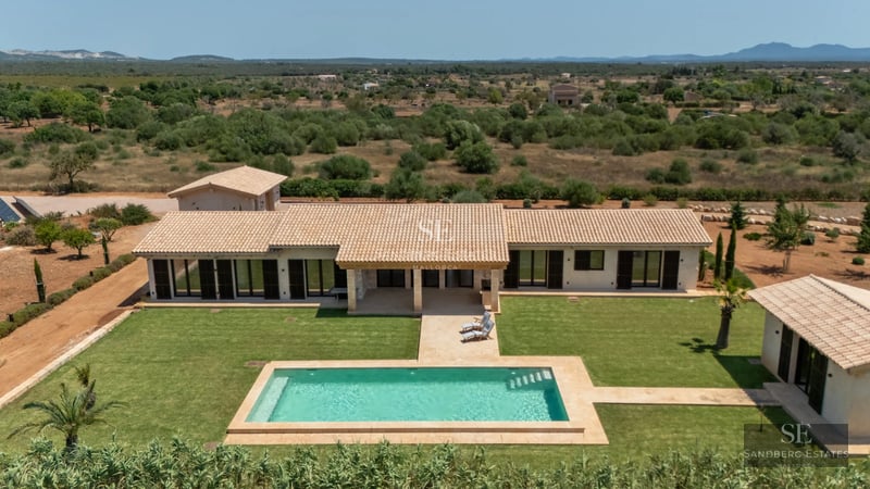 Aerial view of a modern villa with a pool, lush garden, and sleek architectural design. Spacious and bright living spaces.