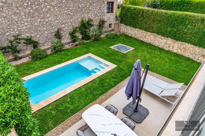 Exterior view of modern villa featuring a swimming pool, lush garden, and expansive windows reflecting sunlight. Avant-garde architectural design.