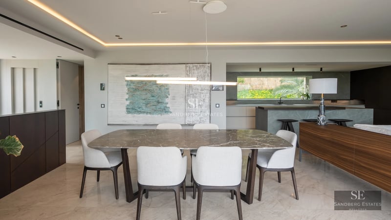 Exterior view of a modern villa with a pool, surrounded by greenery. Minimalist architecture with large windows and luxury finishes.