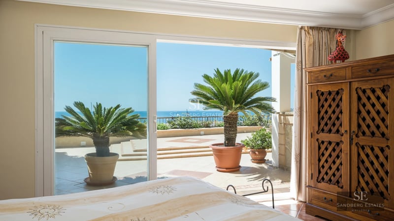 Pool view featuring sun loungers, palm trees, and modern facade. Large windows, warm lighting, and minimalist design.