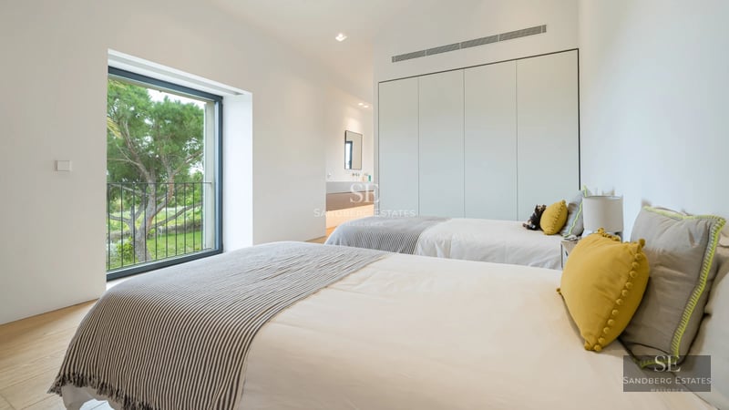 Exterior view of a luxurious villa with an infinity pool, manicured garden, and modern architecture featuring large windows.