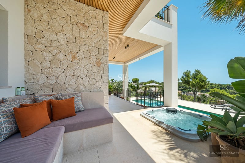 Terrasse avec piscine et vue panoramique sur la mer. Design moderne avec mobilier élégant et végétation luxuriante.