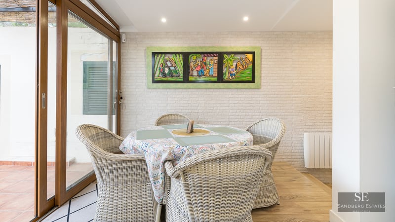 Dining area featuring wicker chairs, a white brick wall, and sliding glass doors.