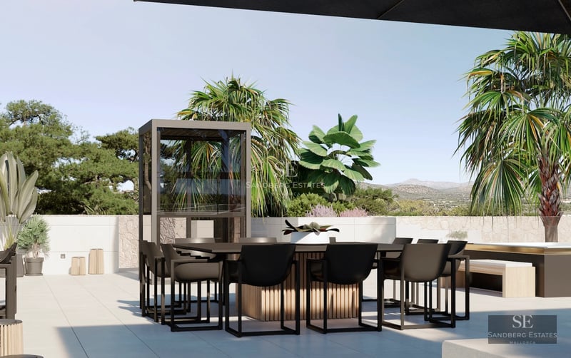 View of the infinity pool with white armchairs and a modern villa with large windows. Green lawn and clear sky.