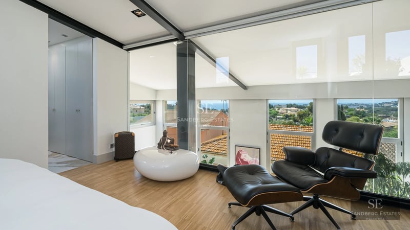 Exterior view of a modern villa featuring a pool, manicured garden, sleek design, and large windows maximizing natural light.