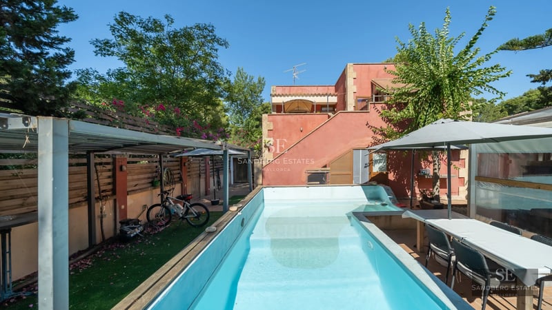 Aerial view of a modern house with turquoise pool, surrounded by greenery. Minimalist design and natural light.