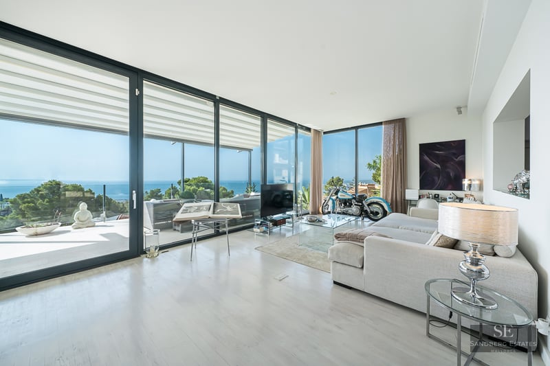 Bright, spacious living room with floor-to-ceiling glass doors, a large white sofa, and a breathtaking view of the ocean.