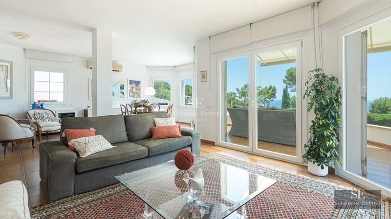 Spacious living room featuring panoramic windows, light wood floors, a modern fireplace, and minimalist designer furniture.